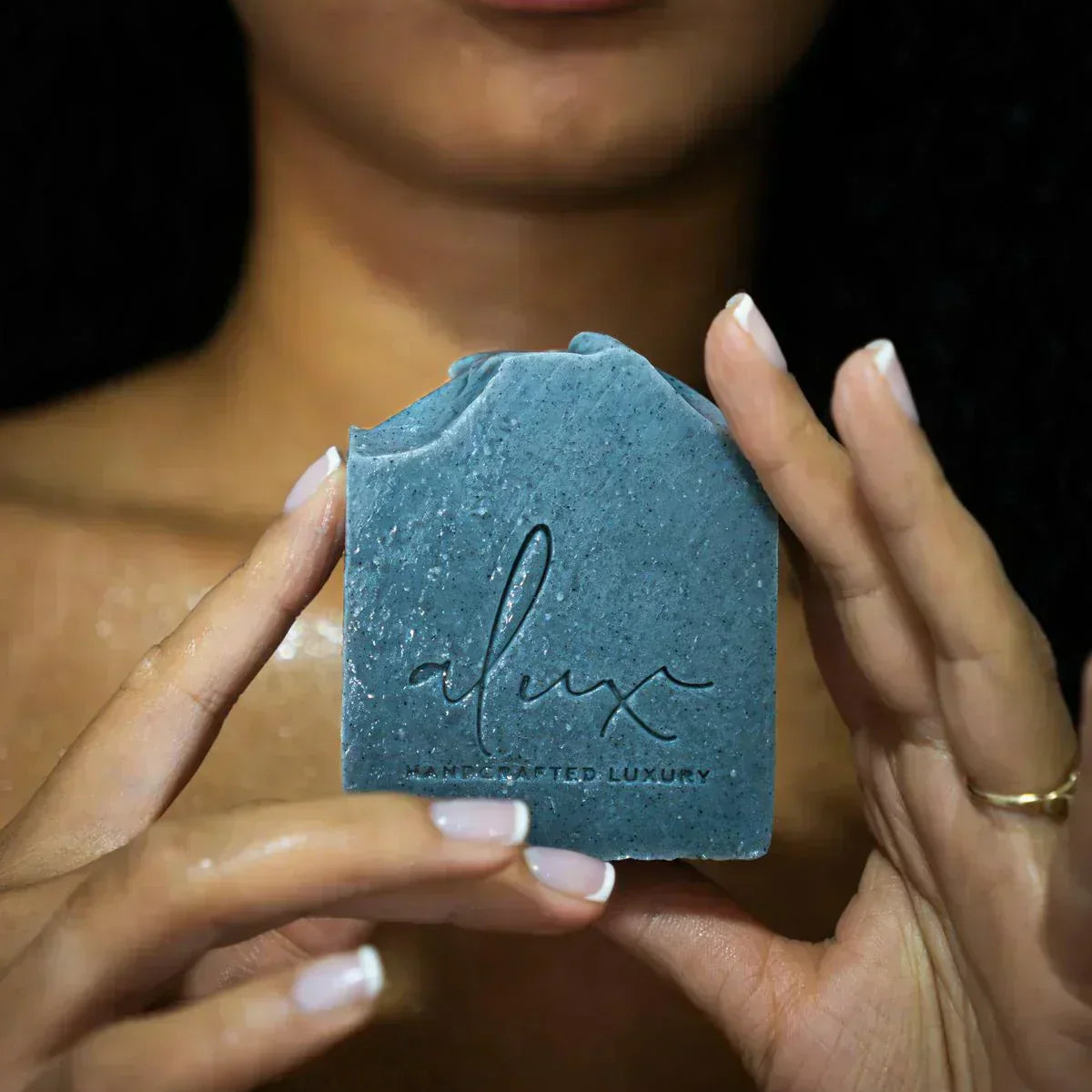 Model using Alux Cosmetics Activated Charcoal Soap for healthy, clear skin.