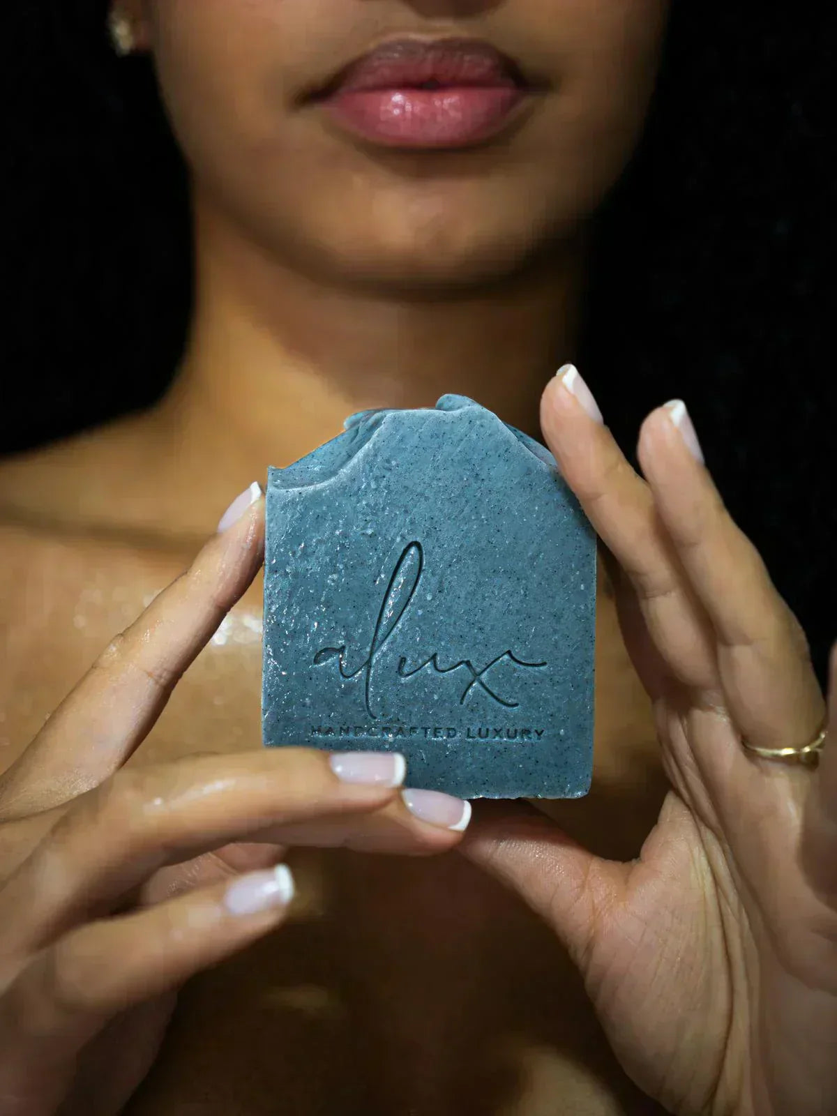 Model using Alux Cosmetics Activated Charcoal Soap for healthy, clear skin.